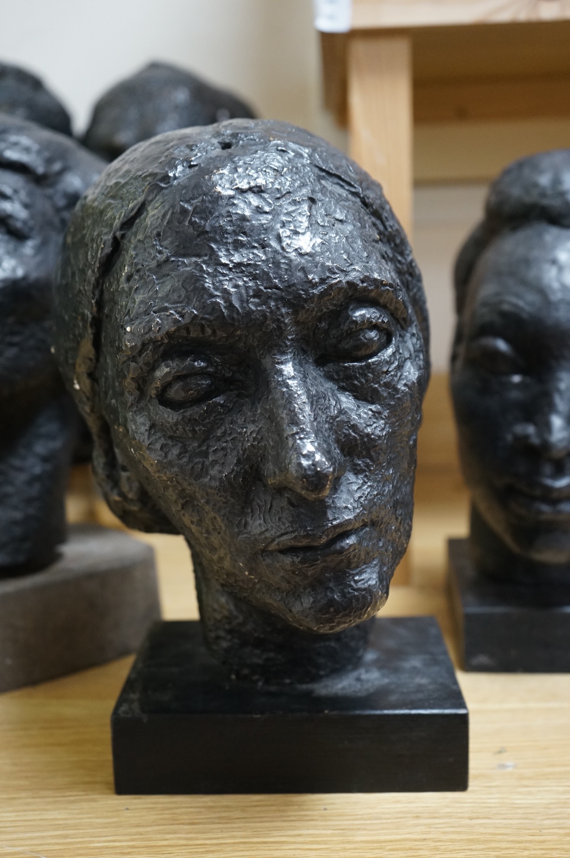 Six black painted composition heads, by Hazel Armour, tallest 49cm